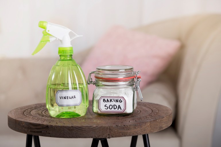 Using baking soda Sodium bicarbonate and white vinegar for home cleaning. White vinegar in spray bottle and baking soda in glass jar.; Shutterstock ID 1703678497; purchase_order: aljazeera ; job: ; client: ; other: