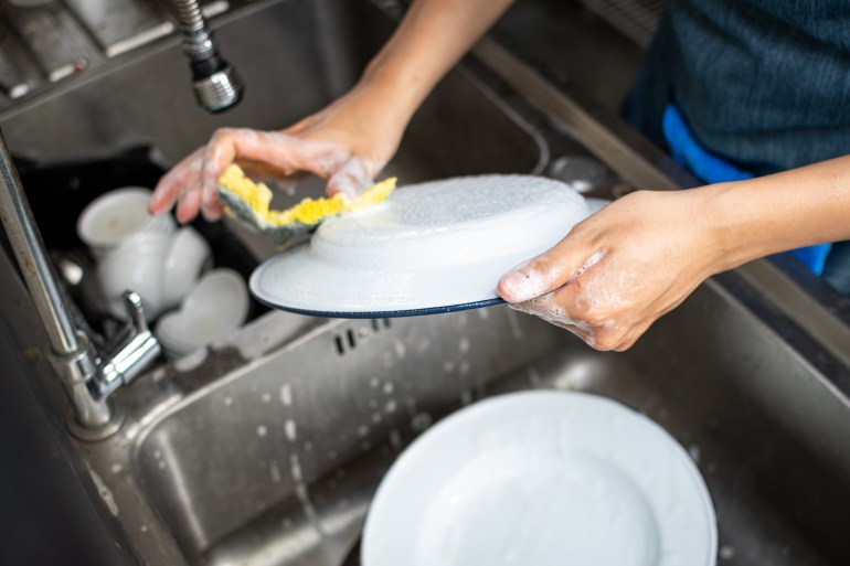 close up shot of dishes being wash by hands of female employee in local restaurant