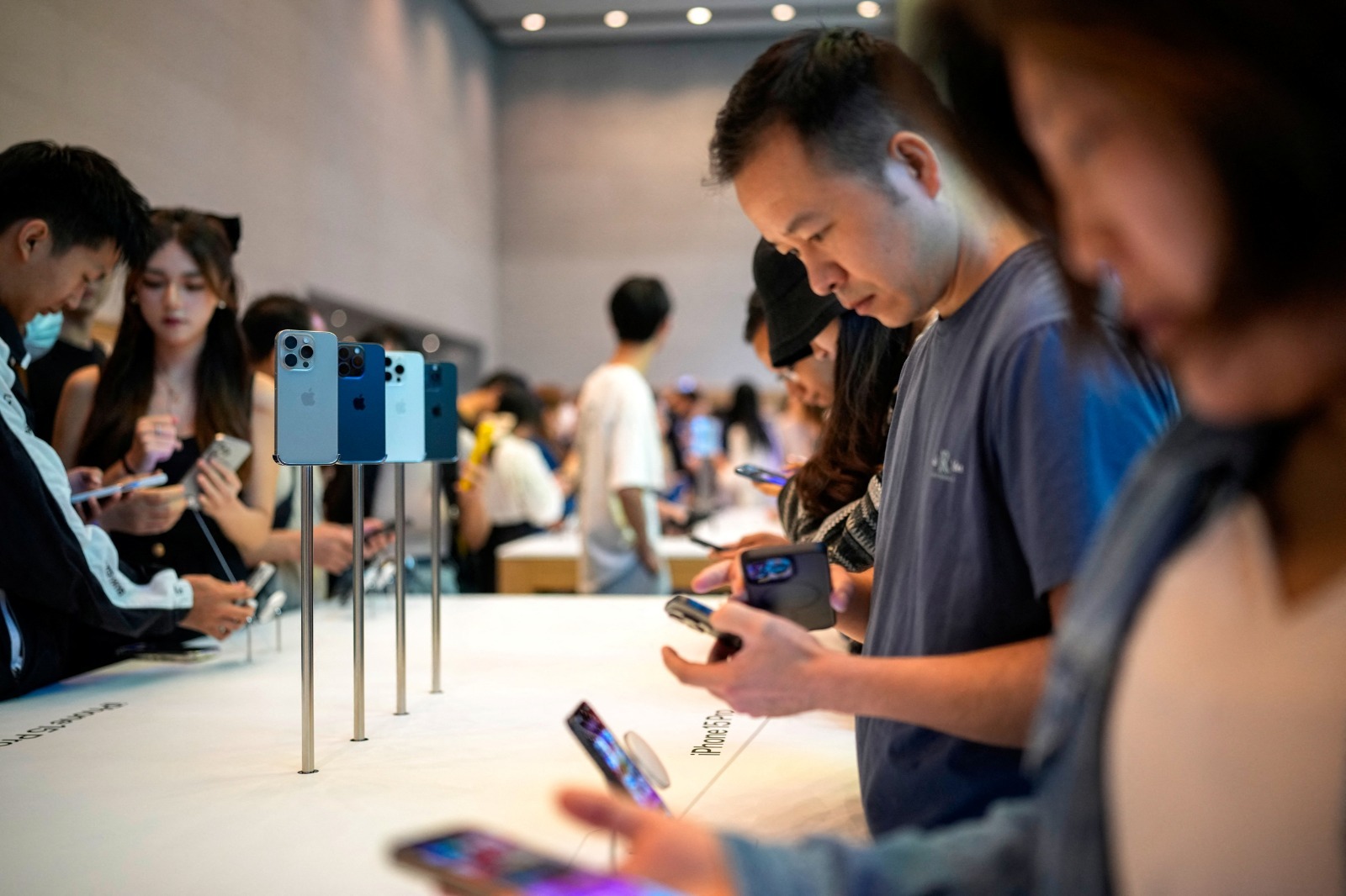 مستخدمون يفحصون أجهزة آيفون 15 داخل أحد متاجر شركة أبل في شنغهاي بالصين. 22 سبتمبر 2023 - Reuters