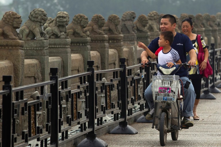 A Chinese child takes a ride on an electric bike past stone lions on Marco Polo bridge also known as Lu Gou Bridge on the 68th anniversary of Japan's surrender in the 1937-1945 anti-Japan war that started from an incident near the bridge in Beijing, China, Thursday, Aug. 15, 2013. (AP Photo/Ng Han Guan)
