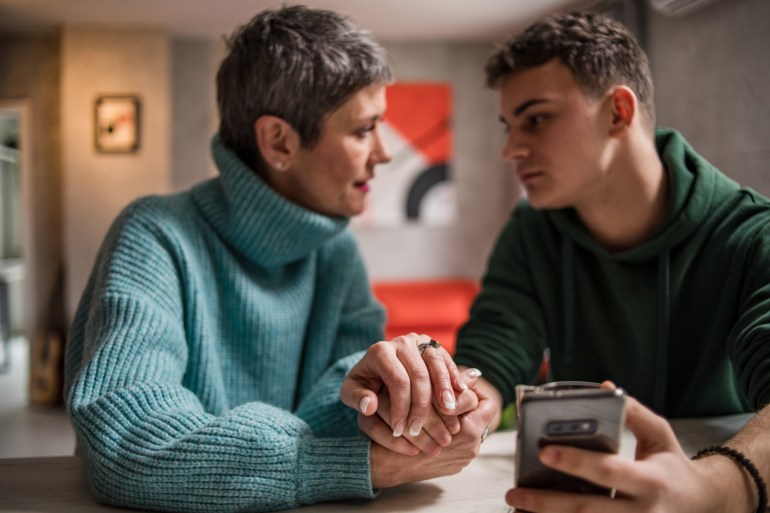 A mother and son are sitting at home and talking, helping her son solve his teenage problems