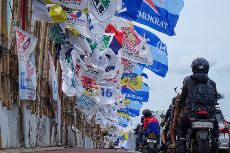 JAKARTA,INDONESIA - JANUARY 23: Motorists drive alongside flags representing various political parties installed along the streets in Jakarta, Indonesia on January 23, 2024. Flags belonging to different political parties and banners showcasing images of candidates are being erected along the sides of the streets as the country gears up for the upcoming elections scheduled to commence on February 14, 2024.