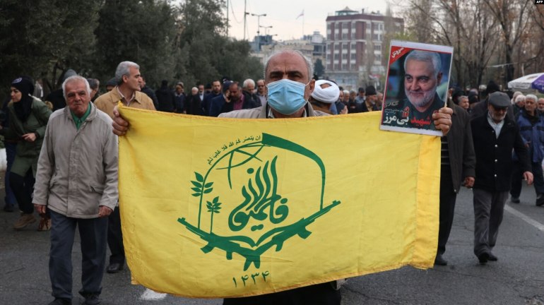 An protester holds the flag of the Afghan Shiite group Liwa Fatemiyoun, a militia formed in 2014 to fight in Syria on the side of the regim, during a protest in support of Yemen and Palestinians, following the Friday noon prayers in Tehran on January 12, 2024, amid continuing battles between Israel and Hamas in Gaza. Portrait (R) shows top Iranian general Qasem Soleimani, who headed the Islamic Revolutionary Guard Corps's foreign operations until he was killed in a US strike in 2020. Iran on January 12 lambasted strikes in Yemen by US and British forces, saying that the attacks against Tehran-backed Huthi rebels were "arbitrary" and a "violation" of international law. (Photo by AFP)