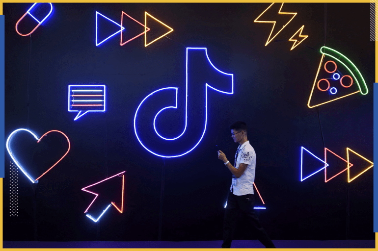 A man holding a phone walks past a sign of Chinese company ByteDance's app TikTok, known locally as Douyin, at the International Artificial Products Expo in Hangzhou, Zhejiang province, China October 18, 2019. Picture taken October 18, 2019. REUTERS/Stringer ATTENTION EDITORS - THIS IMAGE WAS PROVIDED BY A THIRD PARTY. CHINA OUT.