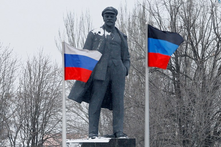 Flags of Russia and the self-proclaimed Donetsk People's Republic wave in the wind near a monument to Soviet state founder Vladimir Lenin during snowfall in the rebel-held city of Donetsk, Ukraine January 24, 2022. REUTERS/Alexander Ermochenko