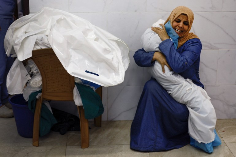 Palestinian woman Inas Abu Maamar, 36, embraces the body of her 5-year-old niece Saly, who was killed in an Israeli strike, at Nasser hospital in Khan Younis in the southern Gaza Strip, October 17, 2023. REUTERS/Mohammed Salem