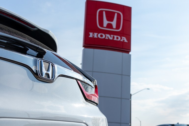 HAMILTON, CANADA - April 18, 2020: Honda emblem on a car at a dealership, with the Honda Motor Company logo on a sign in the background.
