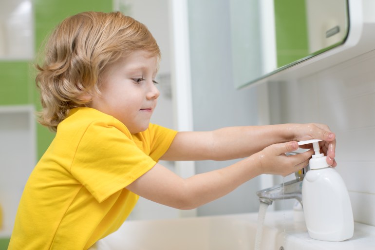 Cute kid boy washing his hands in bathroom