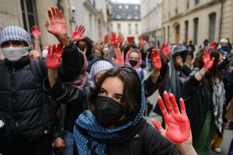 Protesters display mock blood on their hands as they take part in a demonstration in front of the Institute of Political Studies (Sciences Po Paris) occupied by students, in support of Palestinians, in Paris on April 26, 2024. - Students occupied a new building at Sciences Po Paris, in support of Palestinians, a day after police evacuated another of the school's sites, echoing protest action at American universities. (Photo by Dimitar DILKOFF / AFP)