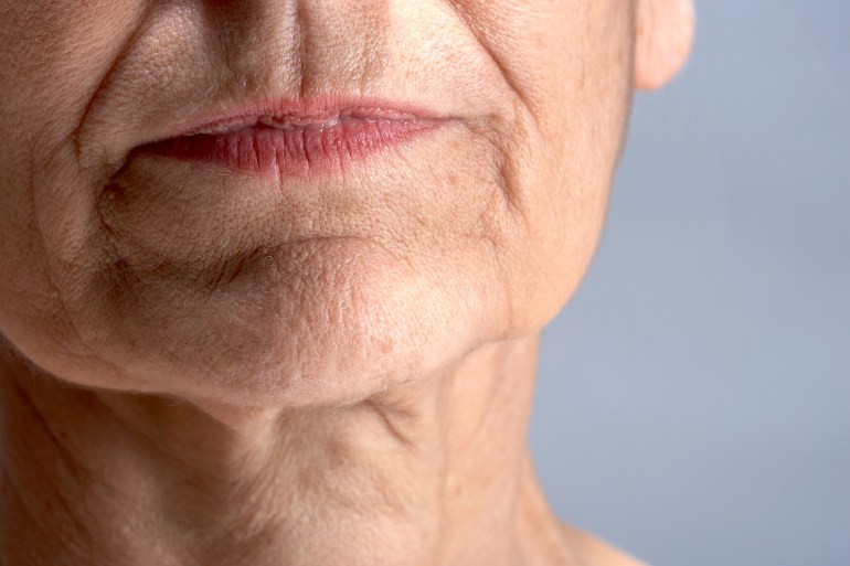 cropped close up of a middle-aged woman's closed mouth and chin, and creases in the skin which have been formed by facial expressions over time