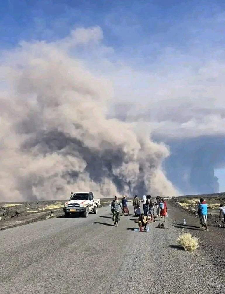 CAPTION CORRECTS HISTORY OF THE VOLCANO - In this photo released by the Afar Government Communication Bureau, people watch ash billow from an eruption of the long-dormant Hayli Gubbi Volcano in Ethiopia's Afar region, Sunday, Nov. 23, 2025. (Afar Government Communication Bureau via AP)
