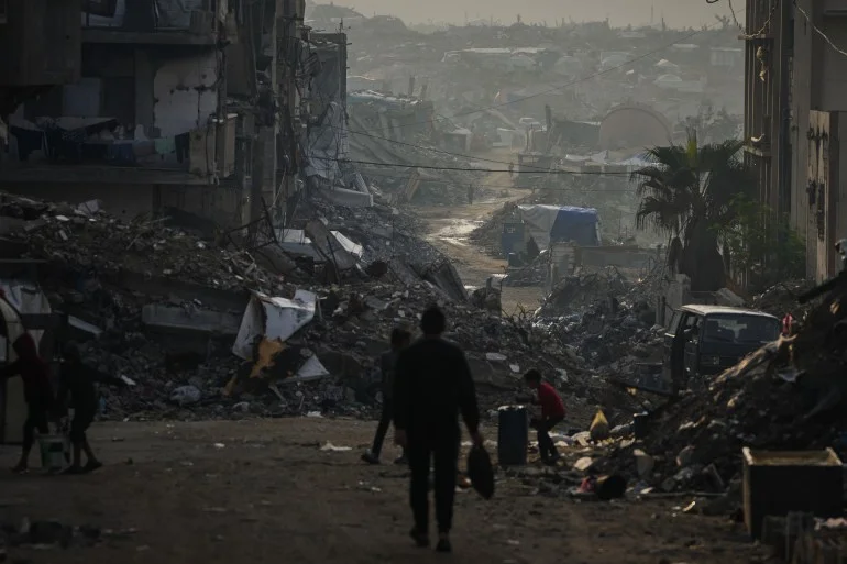 Palestinians walk through the destruction left by the Israeli air and ground offensive in Gaza City, Saturday, Nov. 29, 2025. (AP Photo/Abdel Kareem Hana)