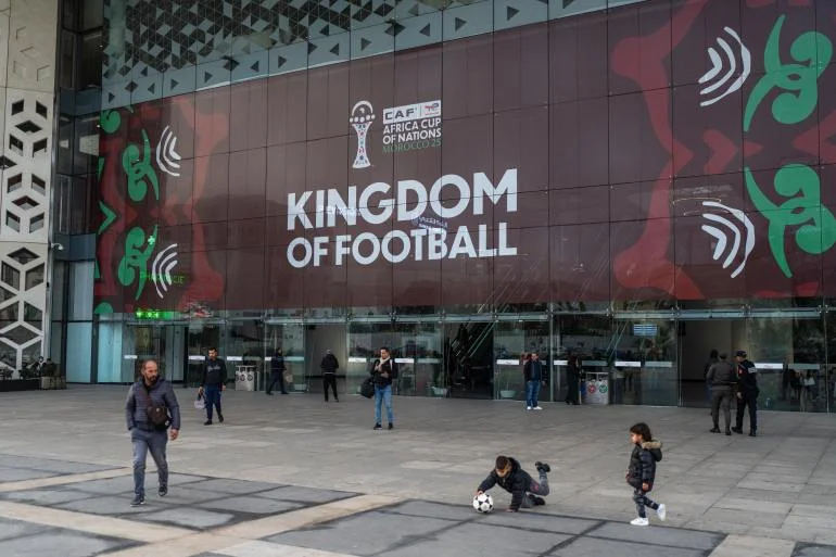 Children play outside a train station with a banner welcoming fans ahead of the Africa Cup of Nations soccer competition, in Rabat, Morocco, Friday, Dec. 19, 2025. (AP Photo/Mosa'ab Elshamy)